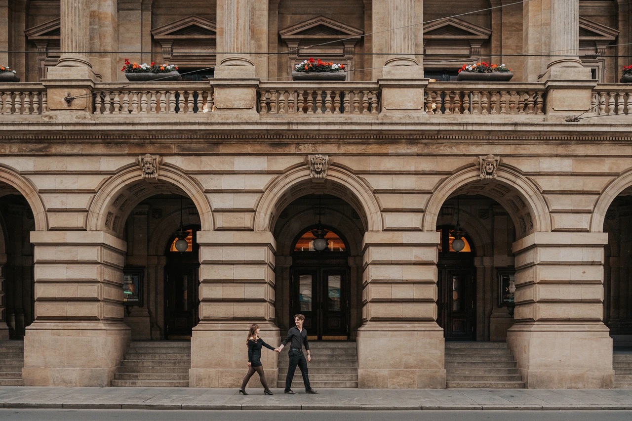 Prague couple photoshoot: couple walking beneath the National Theatre arches. Couple walking beneath the National Theatre arches during a couple photoshoot in Prague.