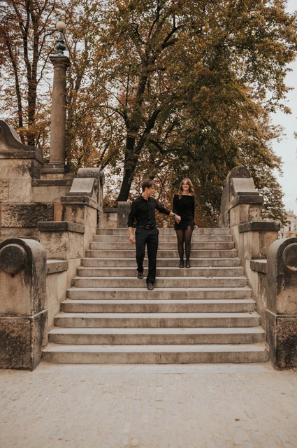 Prague couple photoshoot: couple walking hand in hand down the tree-lined staircase. Couple walking hand in hand down the tree-lined staircase during a couple photoshoot in Prague.