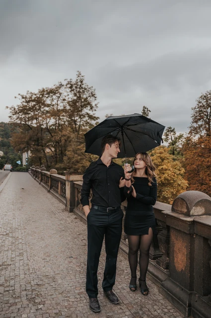 Prague couple photoshoot: couple walking past autumn trees on Legion Bridge. Couple walking past autumn trees on Legion Bridge during a couple photoshoot in Prague.