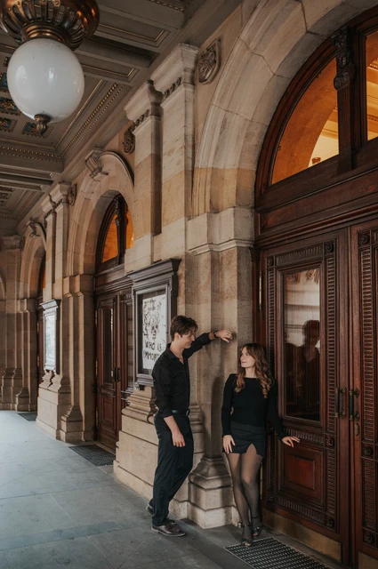 Prague couple photoshoot: couple walking together beneath the theatre arcade. Couple walking together beneath the theatre arcade during a couple photoshoot in Prague.