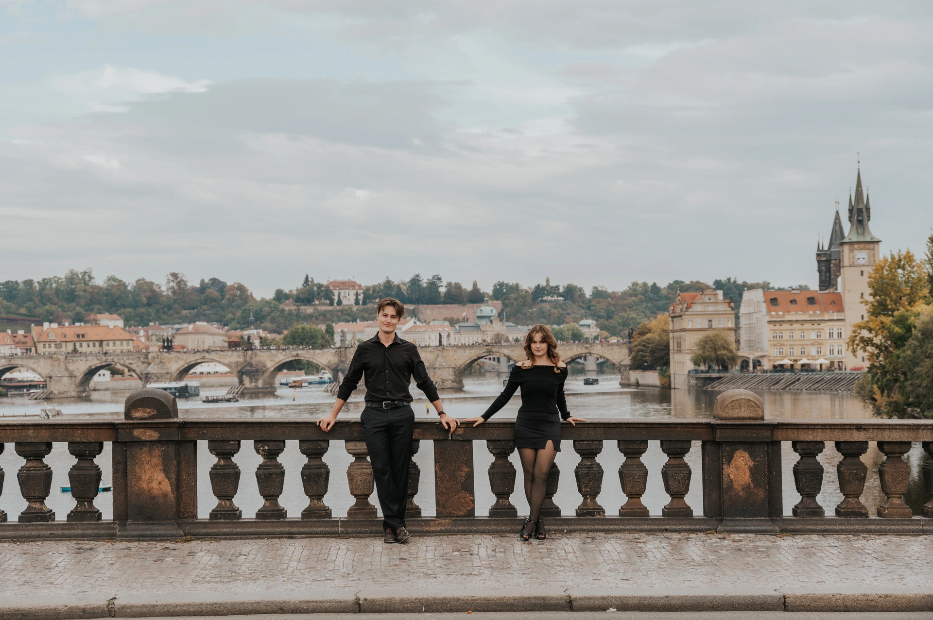 Wide portrait of the couple by the Legion Bridge railing during a couple photoshoot in Prague.