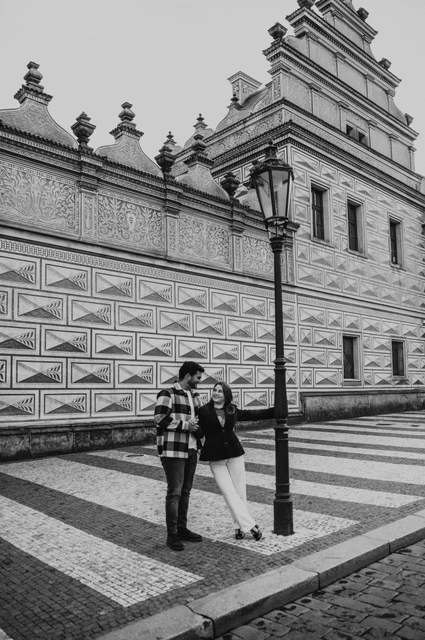 Prague couple photoshoot: a black-and-white castle square portrait Black-and-white photograph of the couple holding hands beside a lamppost in the castle district during their Prague couple photoshoot.