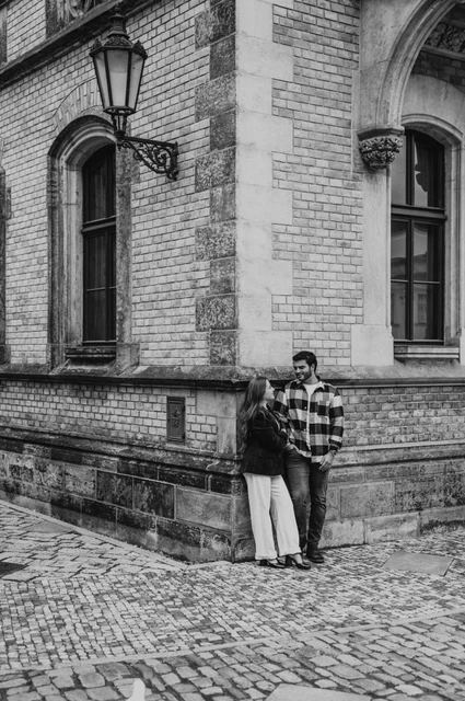 Prague couple photoshoot: a black-and-white portrait at the cathedral corner Black-and-white portrait of the couple together beside a stone cathedral corner and lantern during their Prague couple photoshoot.