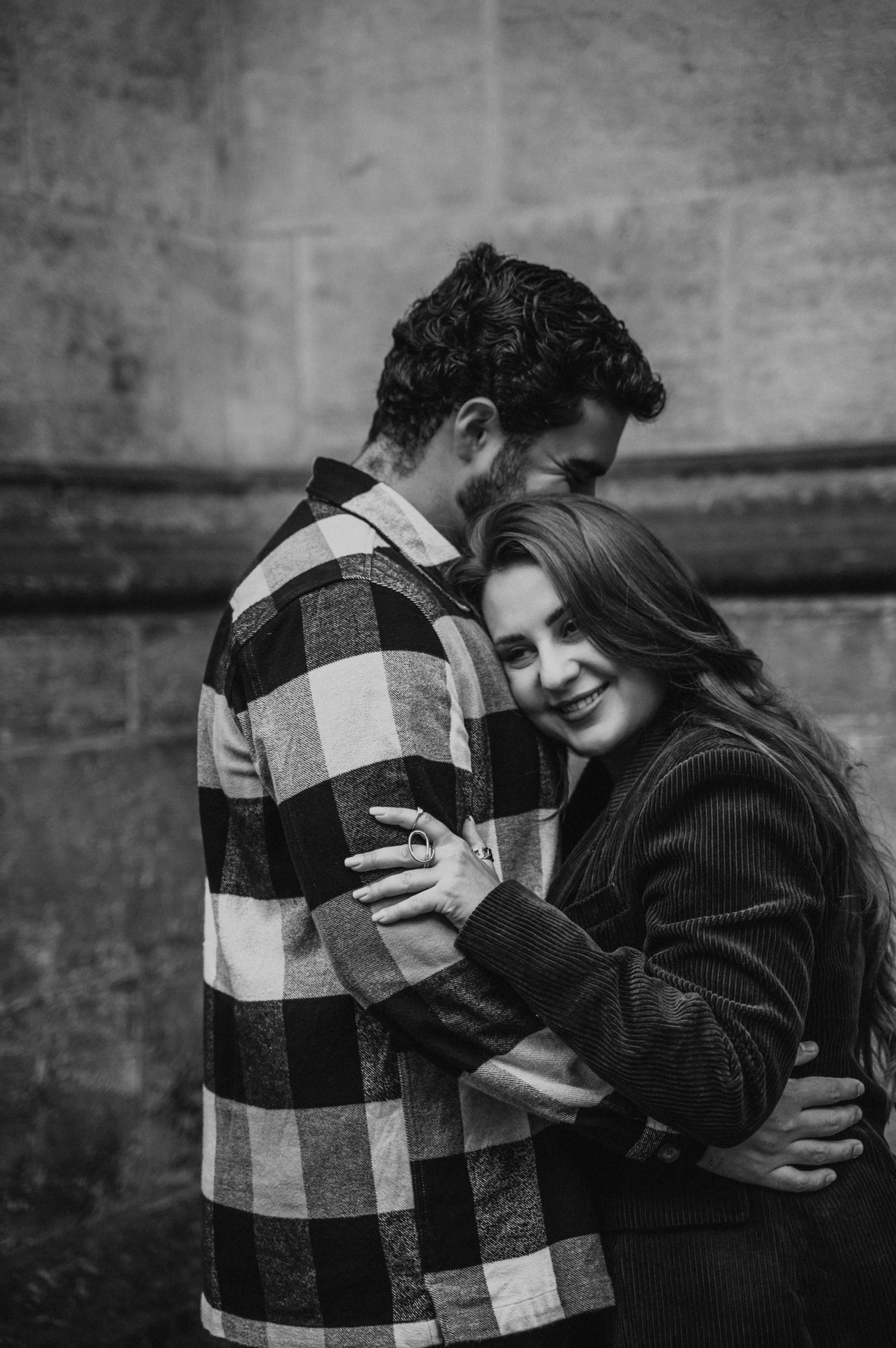Black-and-white portrait of the woman resting against her partner in a close embrace during their Prague couple photoshoot.