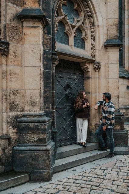Prague couple photoshoot: facing each other on the cathedral steps Couple facing each other on the cathedral steps while the woman holds Amigo during their Prague couple photoshoot.