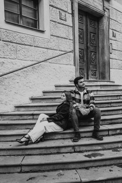 Prague couple photoshoot: a black-and-white portrait on the castle steps Black-and-white photograph of the couple sitting close together on the castle steps during their Prague couple photoshoot.