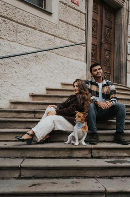 Prague couple photoshoot: a little family of three on the castle steps Couple seated together on stone steps with Amigo sitting in front of them during their Prague couple photoshoot.