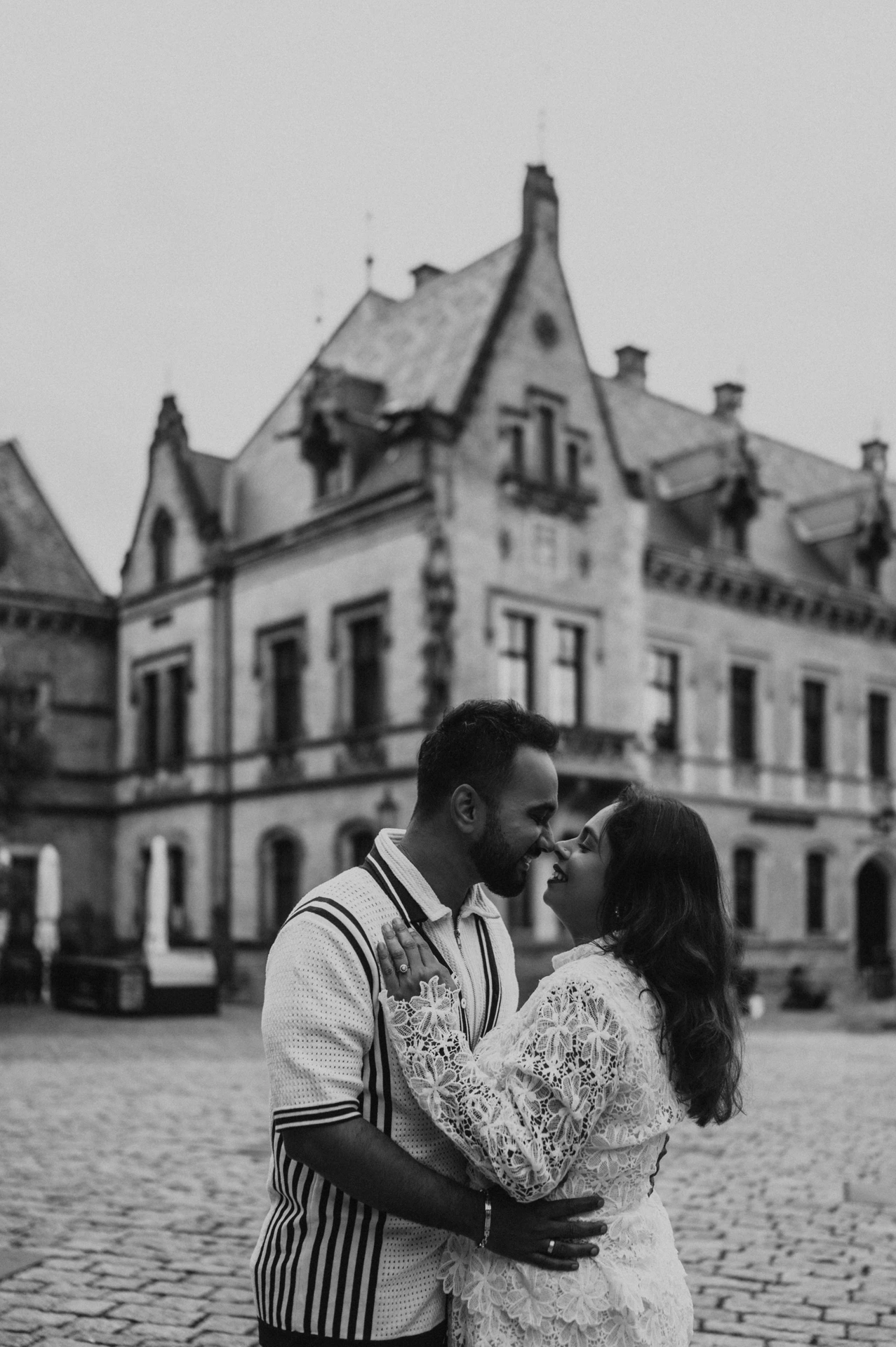 Black-and-white portrait of the couple kissing with castle architecture behind them during their Prague photoshoot.