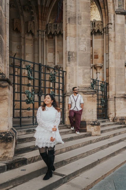 Prague couple photoshoot walking down the cathedral steps Woman walking down the St. Vitus Cathedral steps with her husband behind her during their couple photoshoot in Prague.
