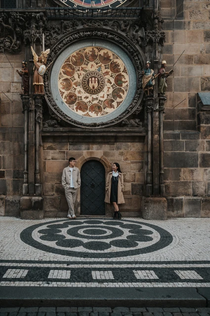 Couple standing on either side of the small doorway beneath Prague's Astronomical Clock during their Prague couple photoshoot.