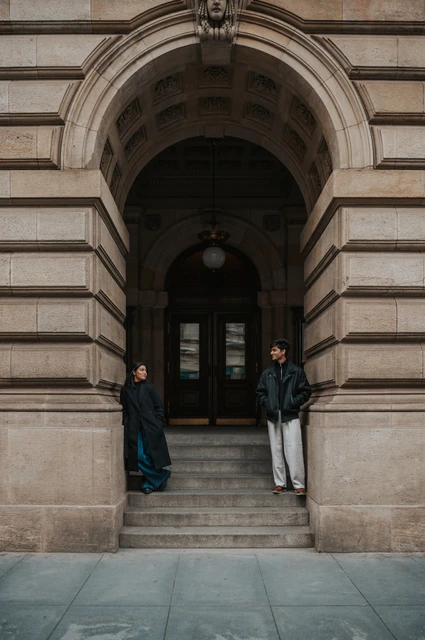 Prague couple photoshoot: facing each other beneath the stone arch Couple facing each other from the stone sides of an arched theatre entrance during their Prague couple photoshoot.