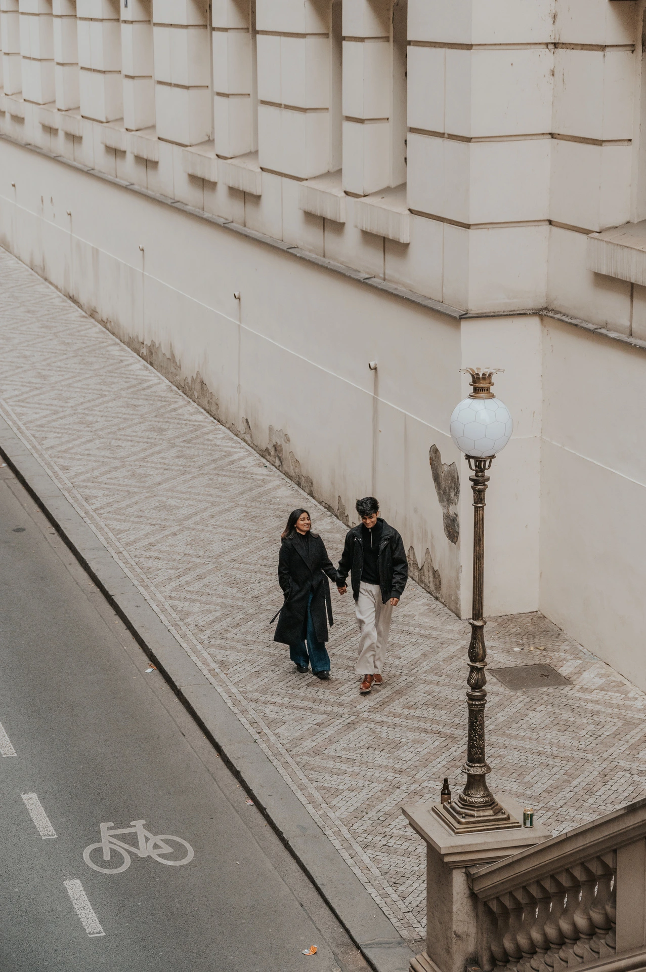 Couple walking close together along the pavement beside the National Theatre during their Prague couple photoshoot.