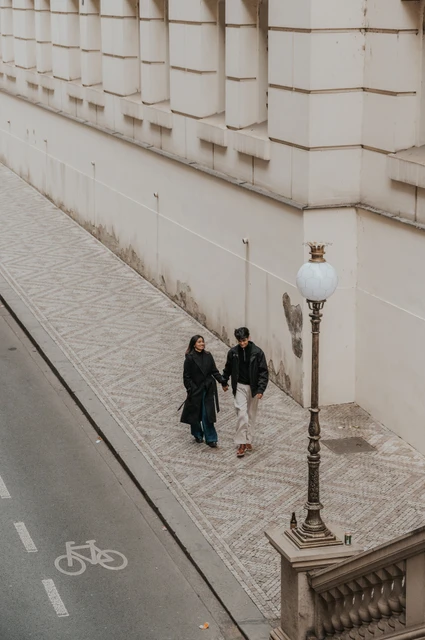 Prague couple photoshoot: a quiet walk along the theatre pavement Couple walking close together along the pavement beside the National Theatre during their Prague couple photoshoot.