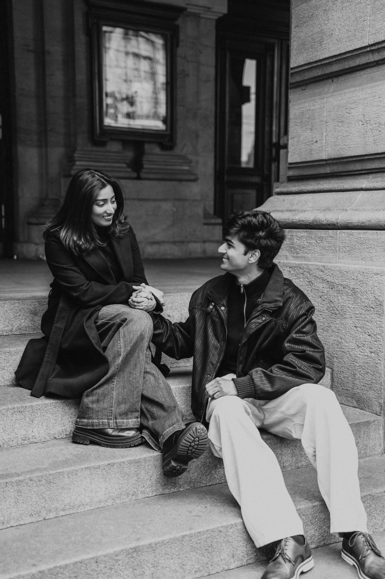 Black-and-white portrait of the couple sitting together on the National Theatre steps during their Prague couple photoshoot.