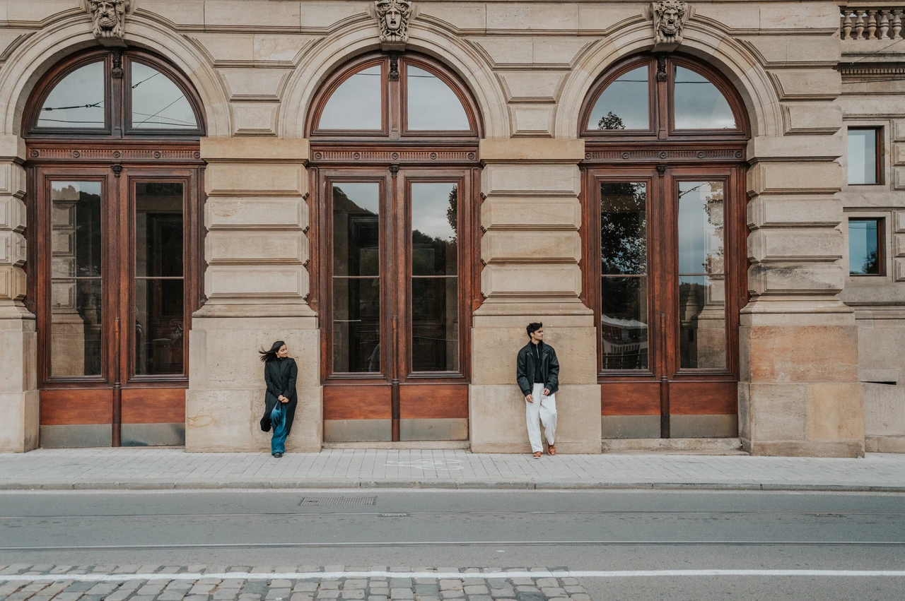 Prague couple photoshoot: together against the ornate theatre facade Couple standing beside a large wooden door with the theatre facade filling the frame during their Prague couple photoshoot.