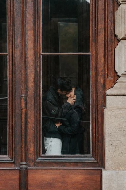 Prague couple photoshoot: an embrace inside the wooden window frame Couple embracing and sharing a kiss inside a tall wooden window frame during their Prague couple photoshoot.