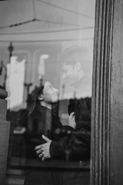 Prague couple photoshoot: a black-and-white portrait behind the theatre window Black-and-white close portrait of the couple looking at each other through reflective theatre window glass during their Prague couple photoshoot.