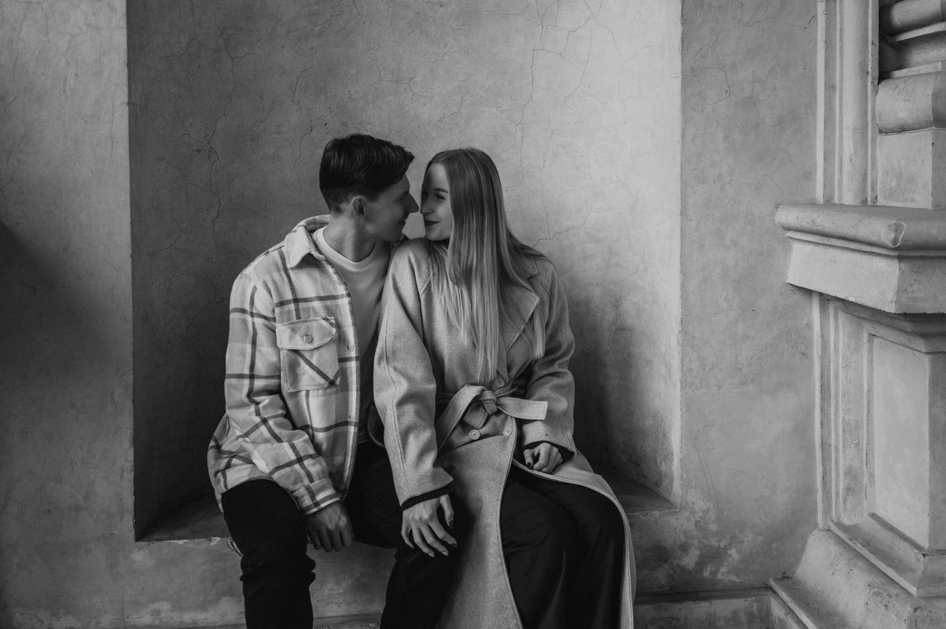 Black-and-white photograph of the couple kissing while seated in a garden alcove during their Prague couple photoshoot.