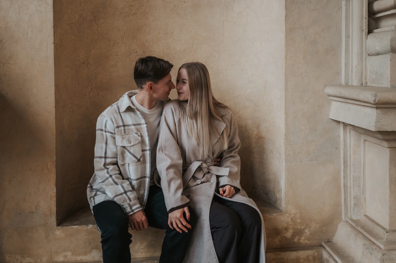 Prague couple photoshoot: a seated kiss beneath the stone alcove Wide photograph of the couple sharing a kiss on a stone alcove bench during their Prague couple photoshoot.