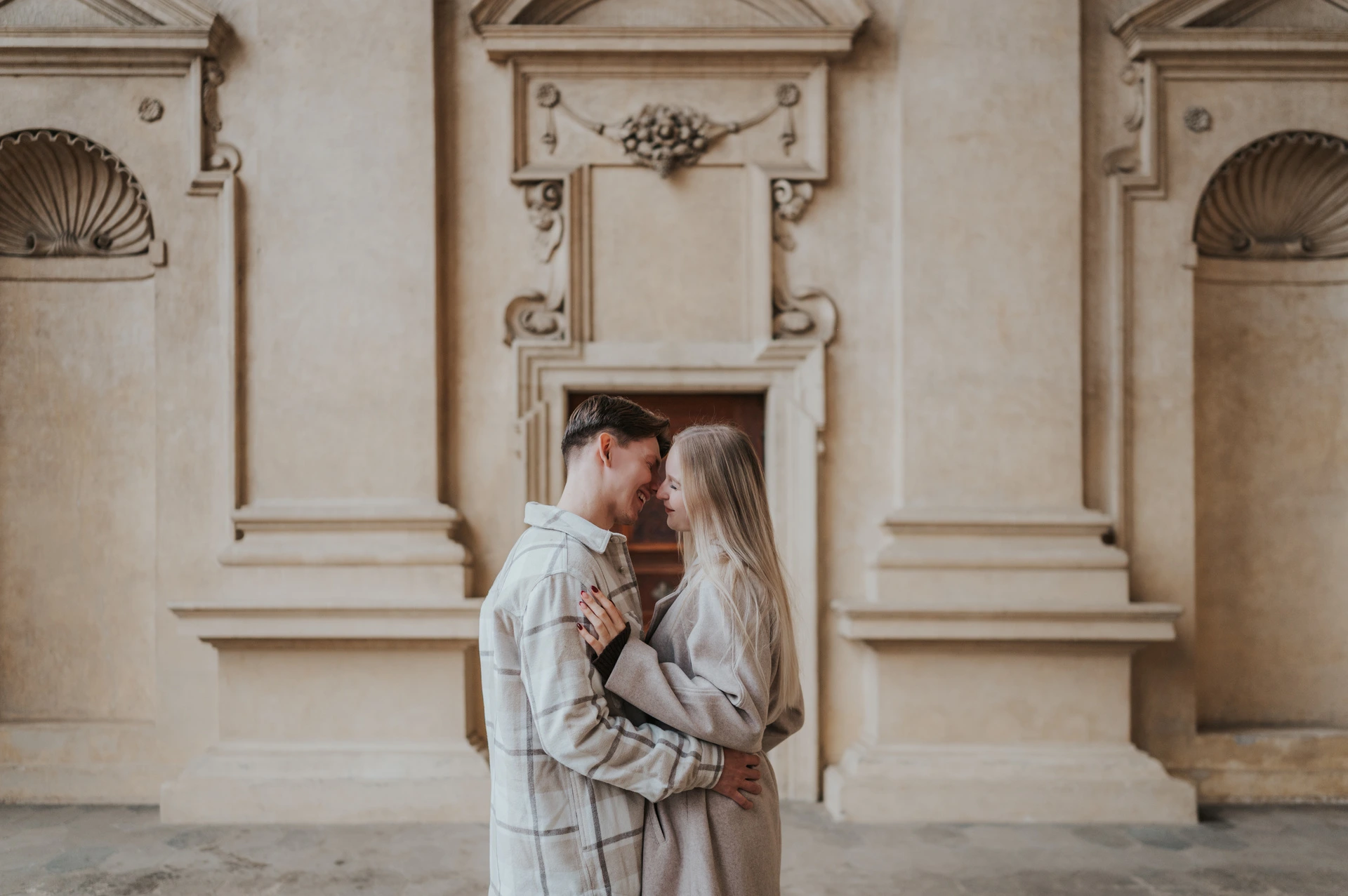 Couple looking at each other in a close embrace in the Wallenstein Garden arcade during their Prague couple photoshoot.