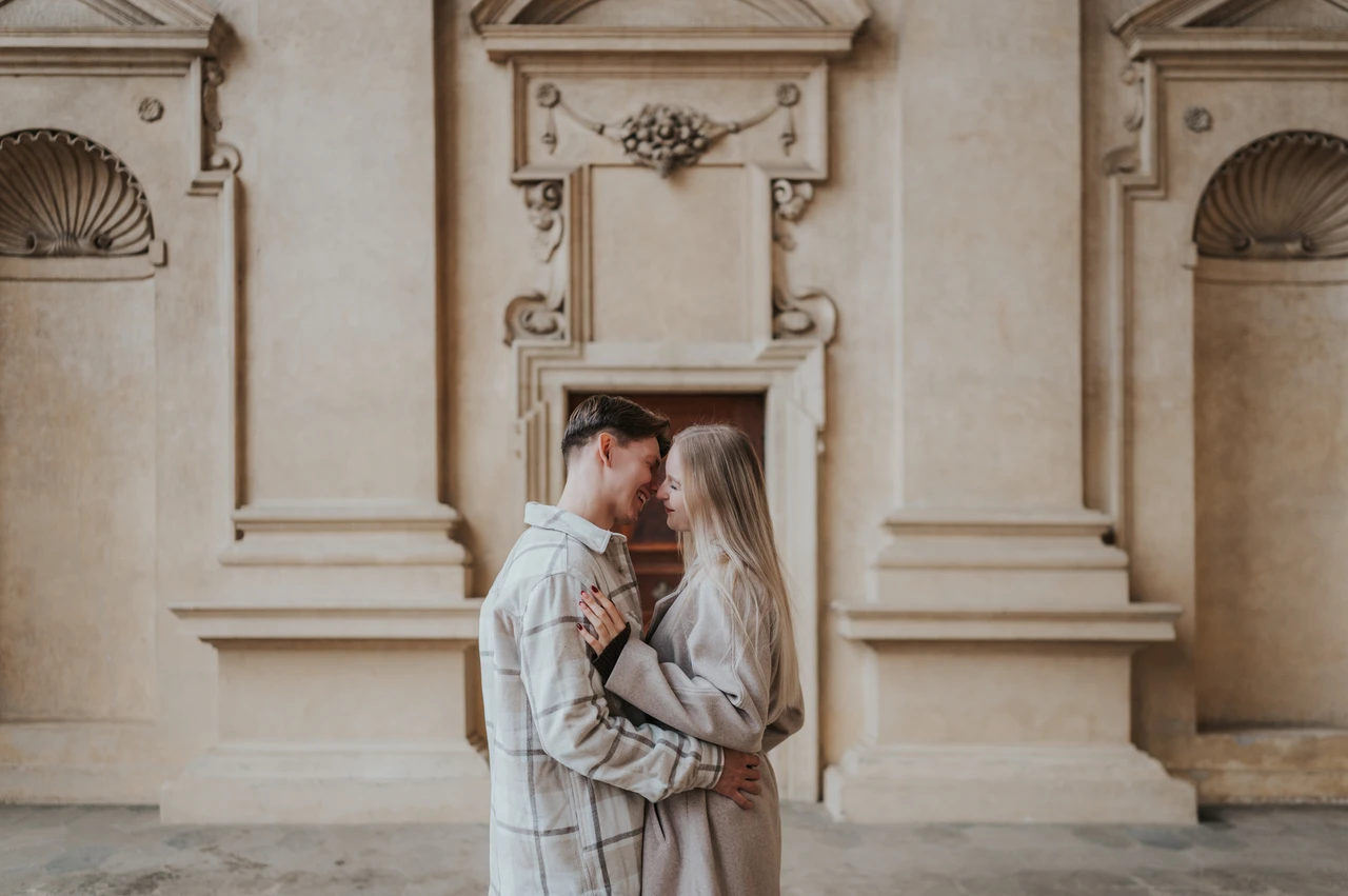 Prague couple photoshoot: an embrace among the arcade details Couple looking at each other in a close embrace in the Wallenstein Garden arcade during their Prague couple photoshoot.