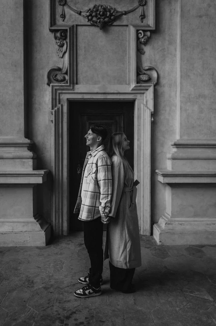 Prague couple photoshoot: a black-and-white doorway portrait Black-and-white portrait of the couple standing together beside the arcade doorway during their Prague couple photoshoot.