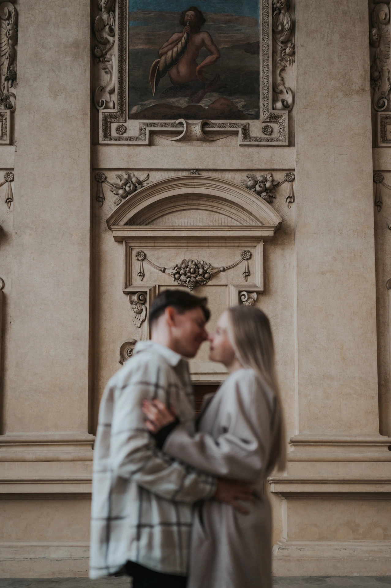 Soft-focus portrait of the couple kissing with a fresco above them during their Prague couple photoshoot.
