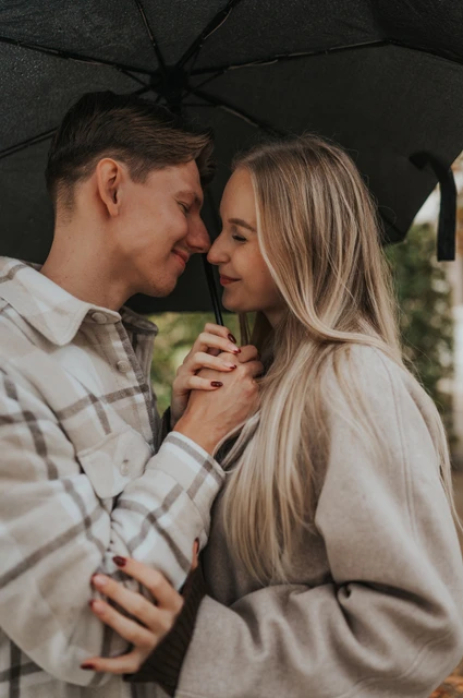 Prague couple photoshoot: a quiet close-up under the umbrella Close portrait of the couple touching foreheads and holding hands beneath their umbrella during their Prague couple photoshoot.