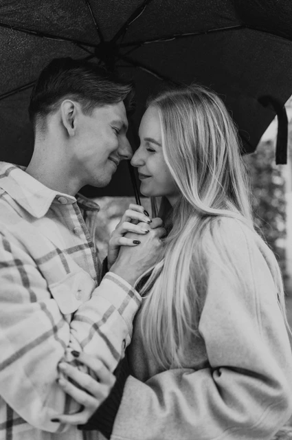 Prague couple photoshoot: a black-and-white close-up beneath the umbrella Black-and-white close portrait of the couple touching foreheads beneath a black umbrella during their Prague couple photoshoot.