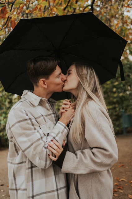Prague couple photoshoot: a kiss beneath the black umbrella Couple kissing beneath a black umbrella with their hands held close together during their Prague couple photoshoot.