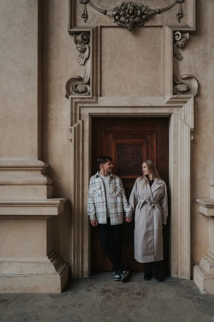 Prague couple photoshoot: side by side in the wooden doorway Couple standing side by side in a carved wooden doorway at Wallenstein Garden during their Prague couple photoshoot.