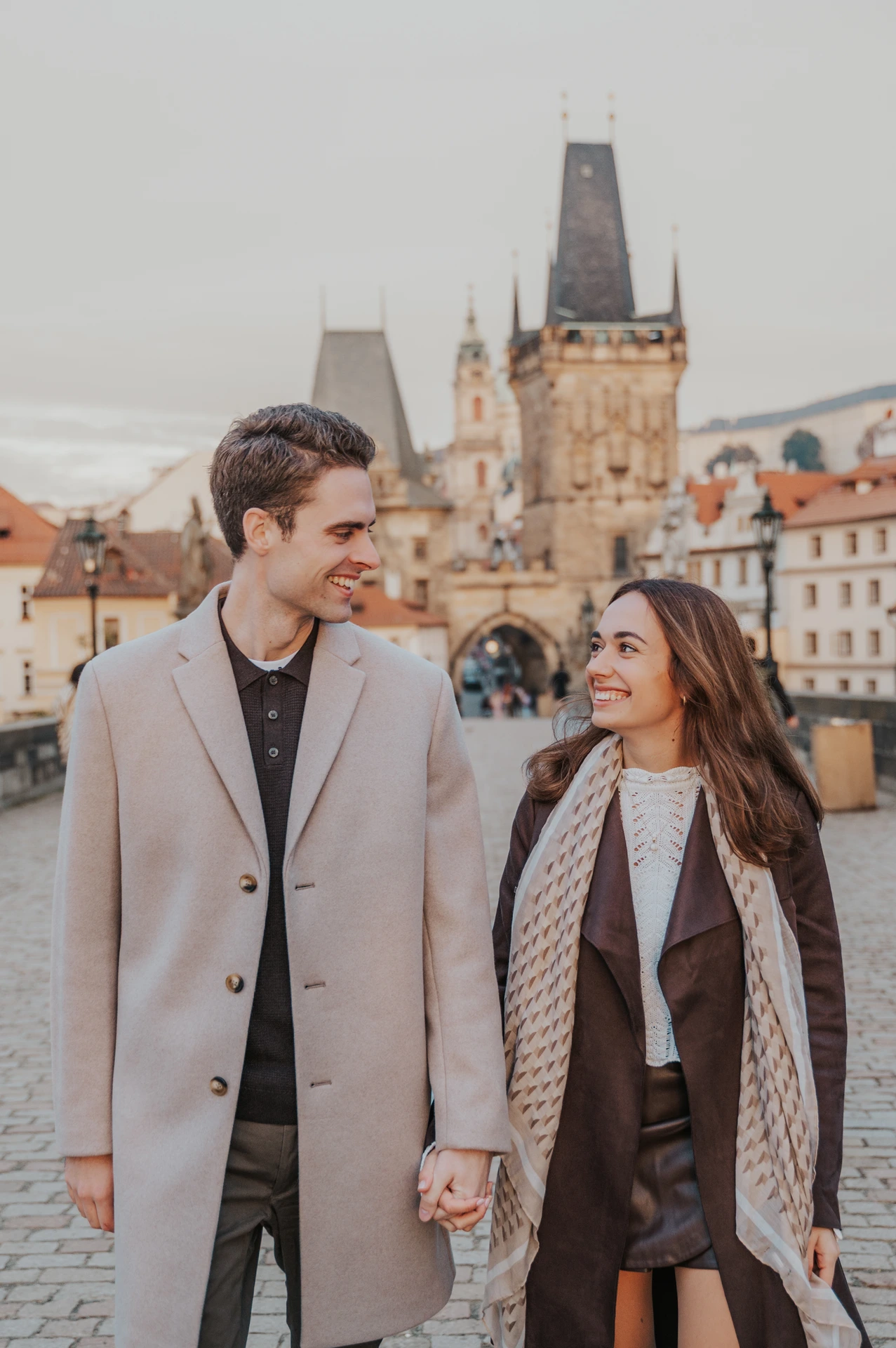 Close portrait of the couple holding hands on Charles Bridge at their Prague engagement photoshoot