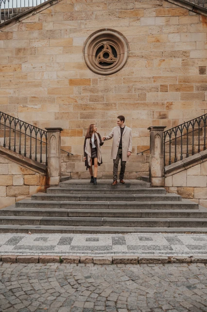 Hand in hand on the bridge stairs Couple holding hands on the stairs beside Charles Bridge during their engagement photoshoot in Prague