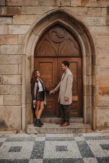 Engagement portrait in a Prague doorway Couple standing together in an arched doorway near Charles Bridge during their engagement photoshoot in Prague