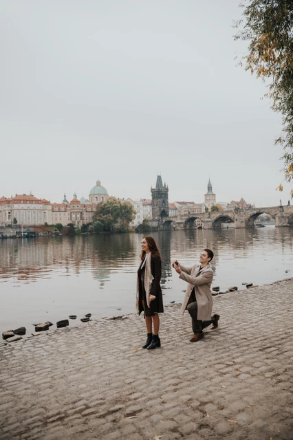 Proposal photoshoot on the Kampa riverbank Man kneeling with a ring in front of his partner on the Kampa riverbank during their Prague proposal photoshoot