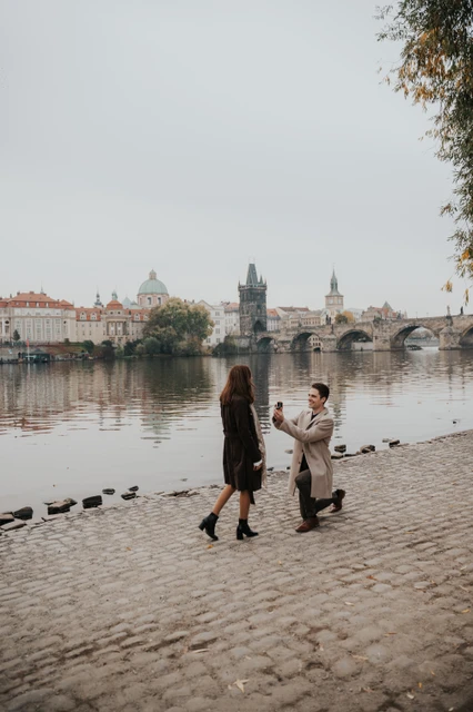 Man proposing to his partner on the cobbled Kampa riverbank during their Prague proposal photoshoot