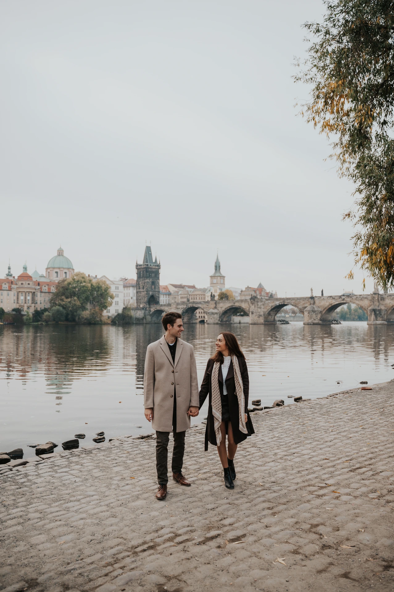 Couple walking towards the camera on the Kampa riverbank during their engagement photoshoot in Prague