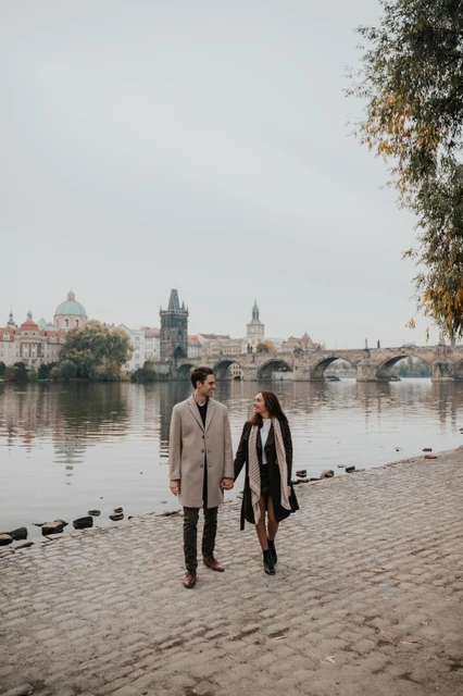 A walk along the Kampa riverbank Couple walking towards the camera on the Kampa riverbank during their engagement photoshoot in Prague