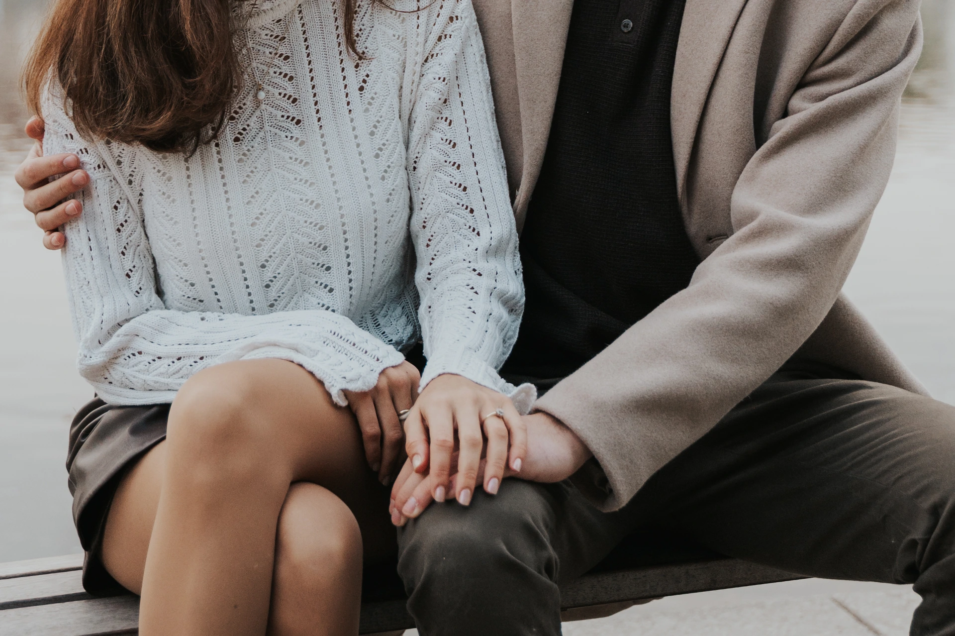Close detail of the couple's hands and engagement ring on a riverside bench after their Prague proposal photoshoot