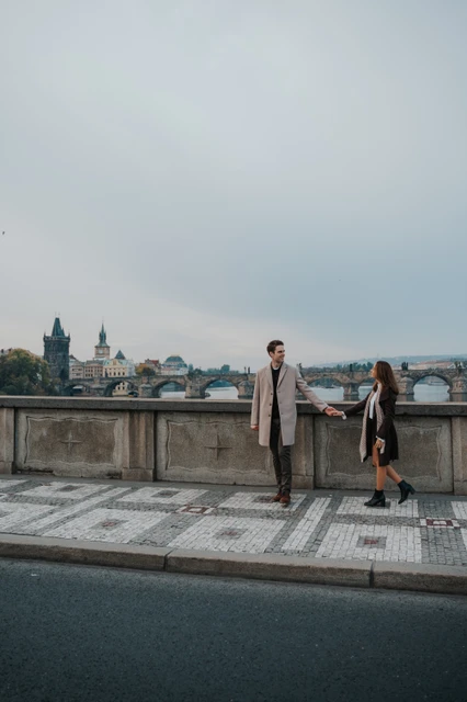 Hand in hand beside the river Couple walking hand in hand beside the river during their engagement photoshoot in Prague