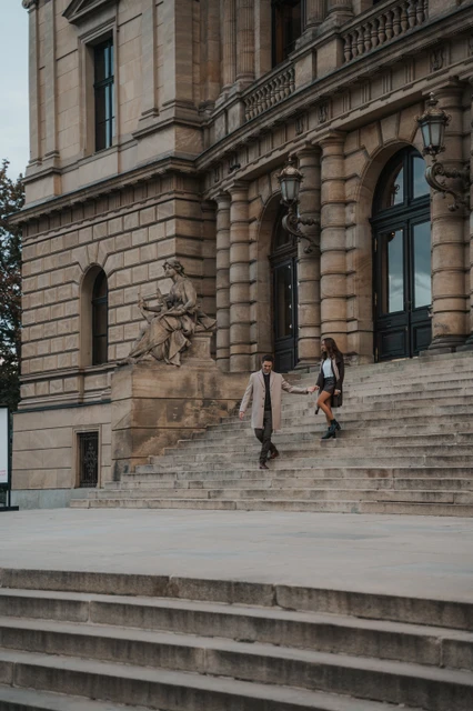 Walking down Prague's stone steps Couple descending broad stone steps during their Prague engagement photoshoot