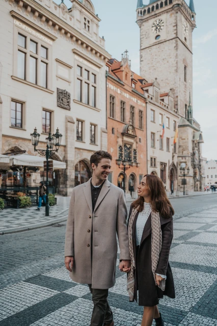 An engagement walk through Prague Old Town Couple walking together near the Old Town Hall during their engagement photoshoot in Prague