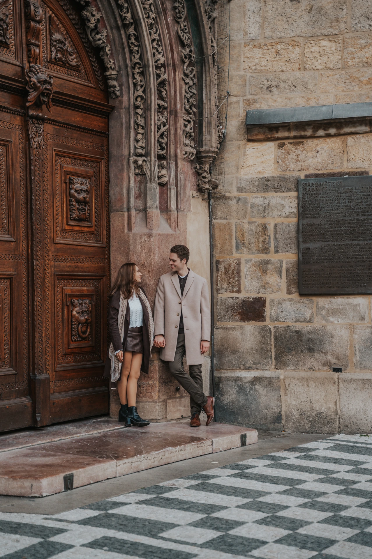 Couple standing at an ornate doorway in Prague Old Town during their engagement photoshoot