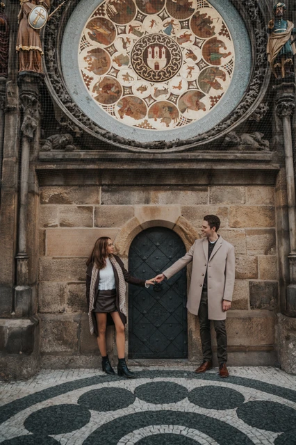 A shared look beneath the Astronomical Clock Couple looking at each other beneath the Astronomical Clock during their engagement photoshoot in Prague