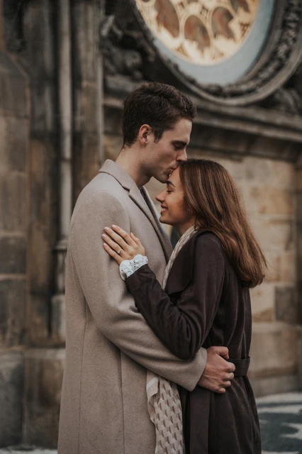 An embrace beneath the calendar dial Couple embracing beneath the Astronomical Clock's calendar dial during their engagement photoshoot in Prague