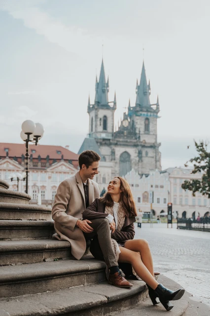 Together on the Old Town Square steps Couple sitting together on stone steps in Old Town Square at their Prague engagement photoshoot