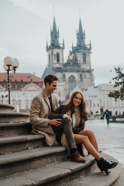 A quiet moment in Old Town Square Couple relaxing on steps in Old Town Square during their Prague engagement photoshoot