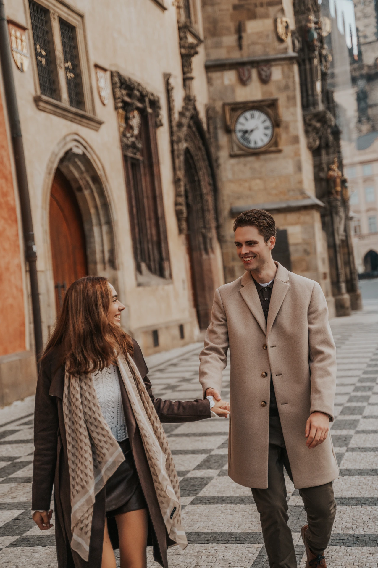 Couple walking hand in hand beside the Old Town Hall during their engagement photoshoot in Prague