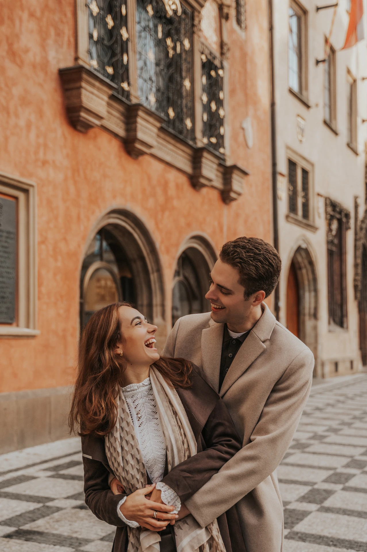 Couple embracing beside the façades of Old Town during their engagement photoshoot in Prague