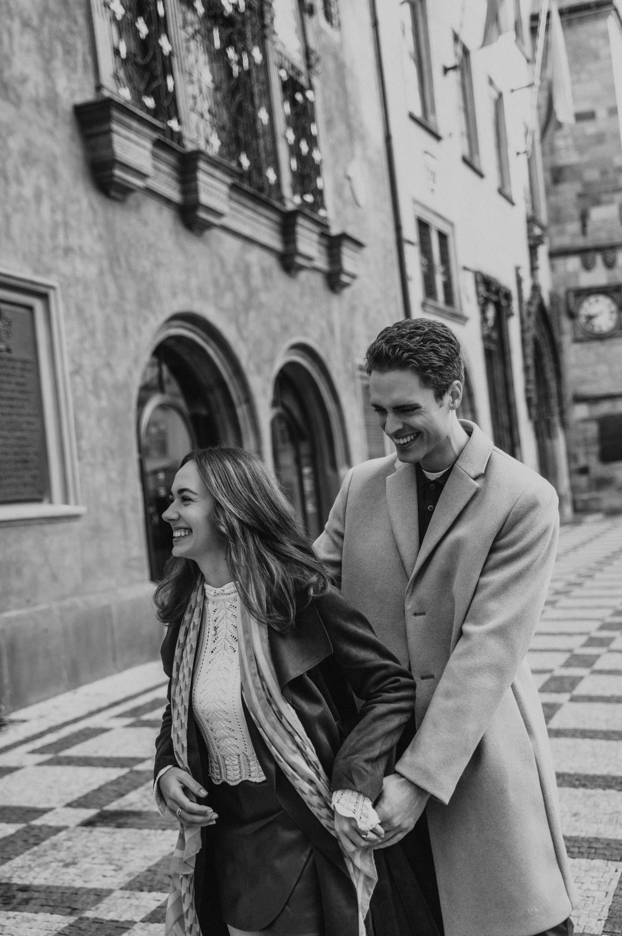 Black and white photograph of the couple embracing beside an Old Town façade during their Prague engagement photoshoot